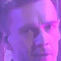 a close up of a man 's face with a blue and purple light behind him .