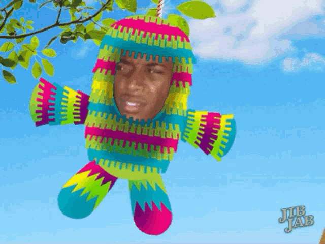 a colorful piñata with a man 's face hanging from a tree branch