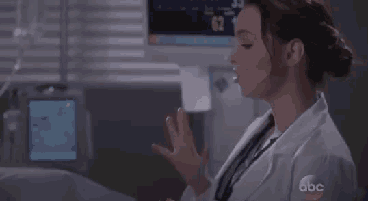 a woman in a lab coat is standing in front of a monitor that says 62 12