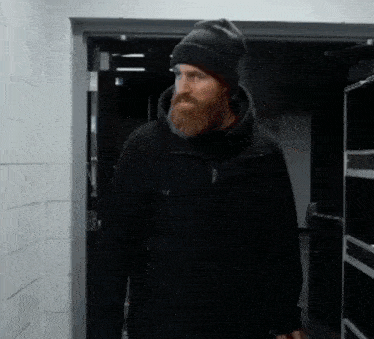 a man with a beard is wearing a black jacket and a black beanie