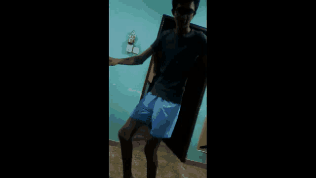 a man in a black shirt and blue shorts is standing in a room