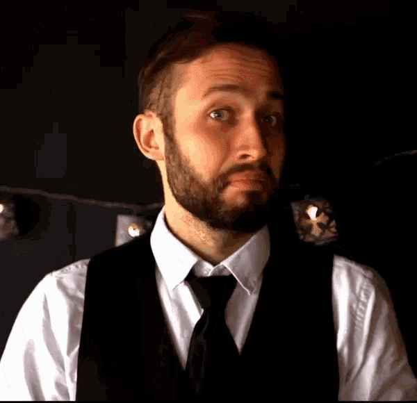 a man with a beard wearing a white shirt and black vest