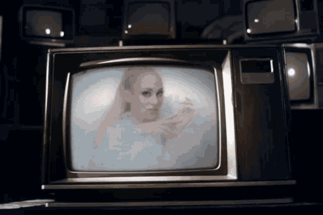 a television screen shows a woman in a bathtub surrounded by other televisions