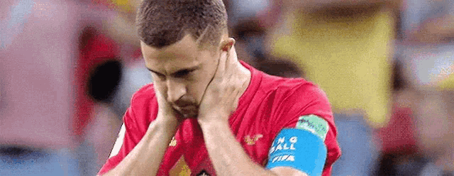 a soccer player is covering his ears with his hands during a soccer game .