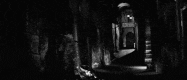 a black and white photo of a dark alleyway with a balcony and a person standing in the middle of it .