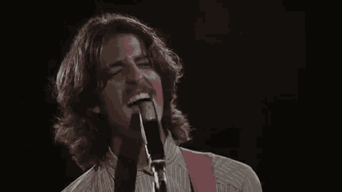 a man singing into a microphone with his eyes closed