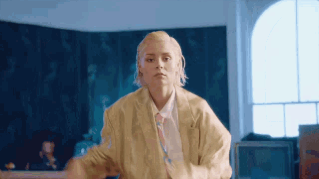 a woman in a suit and tie is dancing in a room