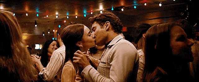 a man and a woman are kissing in front of a crowd of people .