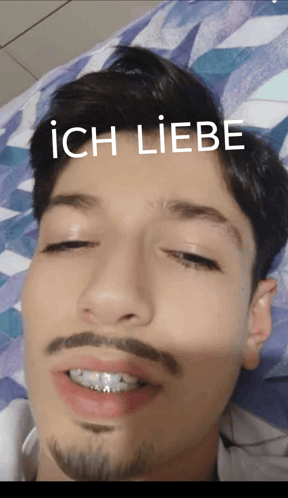 a man with braces on his teeth is laying on a bed with the words ich liebe written on his face