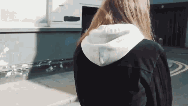 a woman wearing a black jacket and a white hoodie is walking down the street