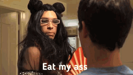 a man in a wig and glasses says " eat my ass "