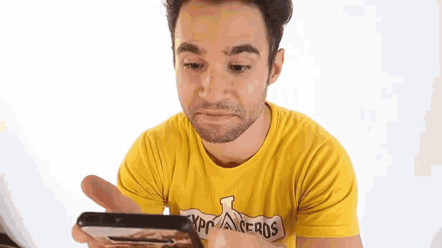 a man wearing a yellow t-shirt that says los angeles is looking at his cell phone
