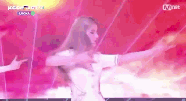 a woman is dancing on a stage with her arms outstretched in front of a pink background .