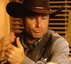 a man is wearing a cowboy hat and giving a thumbs up