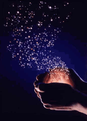 a person holding a glowing object in their hands with stars coming out of it