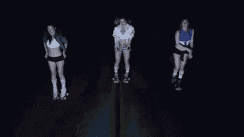 three girls rollerblading on a road with one wearing a number 58 shirt