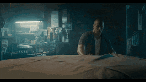 a man in a dark room is looking at a piece of paper