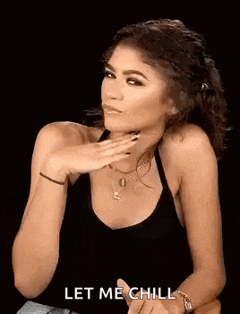 a woman in a black tank top is sitting down with her hand on her chin .
