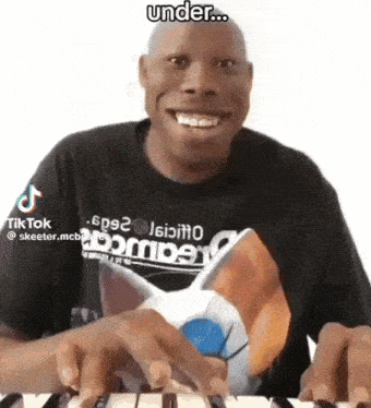 a man is playing a keyboard and smiling while wearing a shirt with a cat on it .