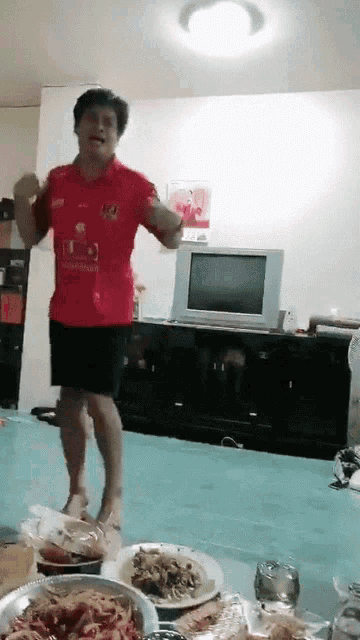 a man wearing a red shirt with the number 10 on it is dancing in a living room