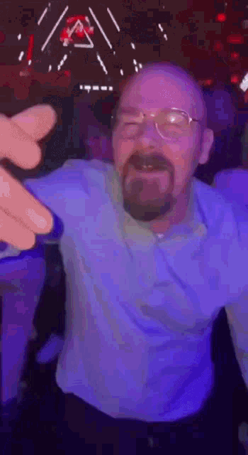 a man with glasses and a beard is dancing in a dark room .