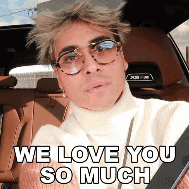 a man wearing glasses and a turtleneck is sitting in a car with the words we love you so much above him