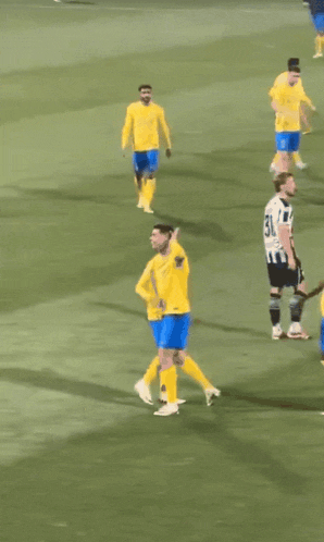 a group of soccer players in yellow and blue uniforms on a field