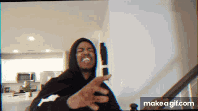 a man in a hoodie is making a funny face while holding a cell phone