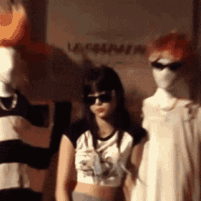 a woman wearing sunglasses is standing next to two mannequins in front of a sign that says ' lee jeans '