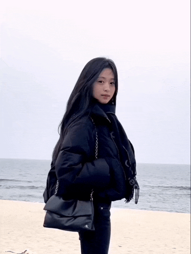 a woman wearing a black jacket and carrying a black ck bag