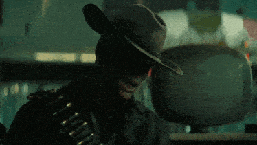 a man wearing a cowboy hat is drinking from a bottle