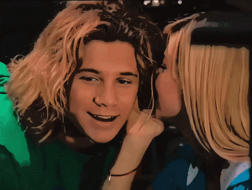 a woman whispering into a man 's ear while he smiles