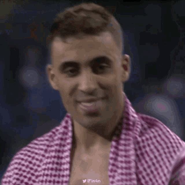 a man wearing a purple and white checkered scarf around his neck is smiling