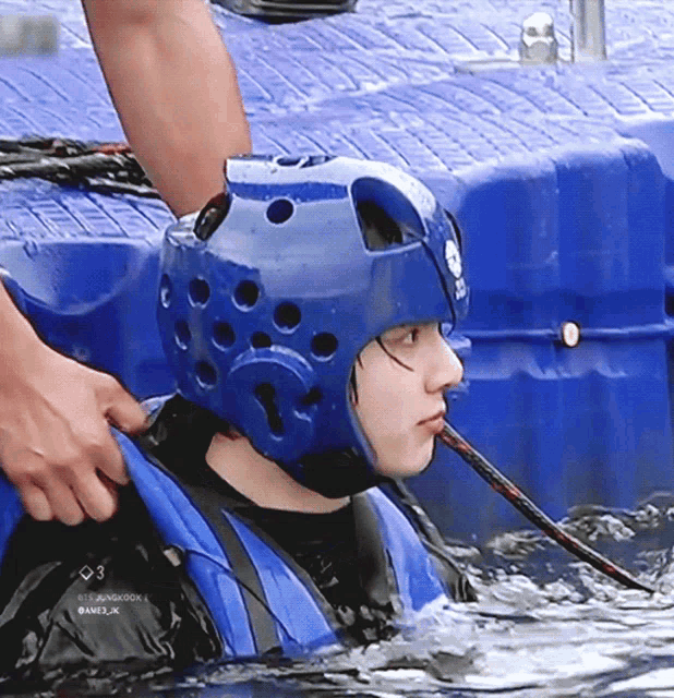 a person wearing a blue helmet and a life jacket is in the water