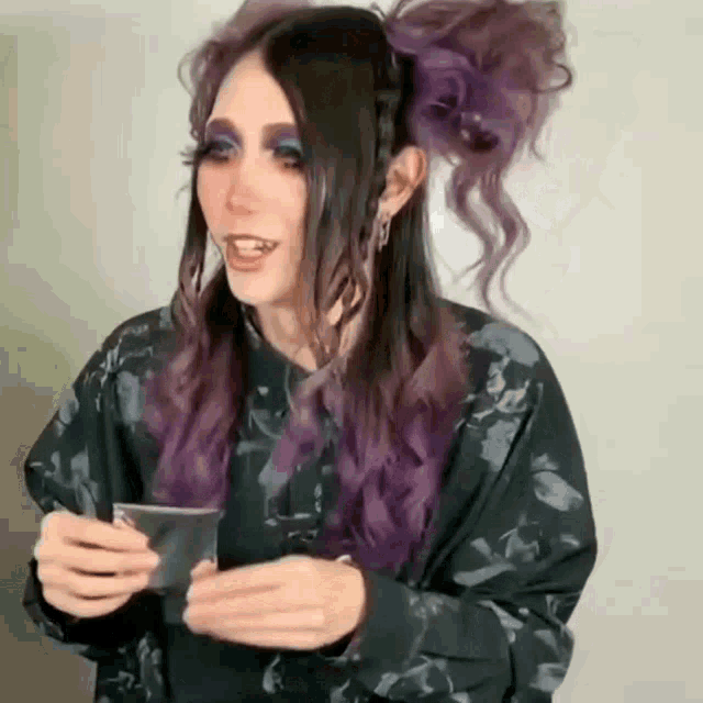 a woman with purple hair is holding a card in her hand