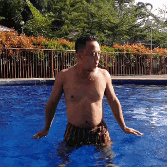 a man without a shirt is standing in a pool