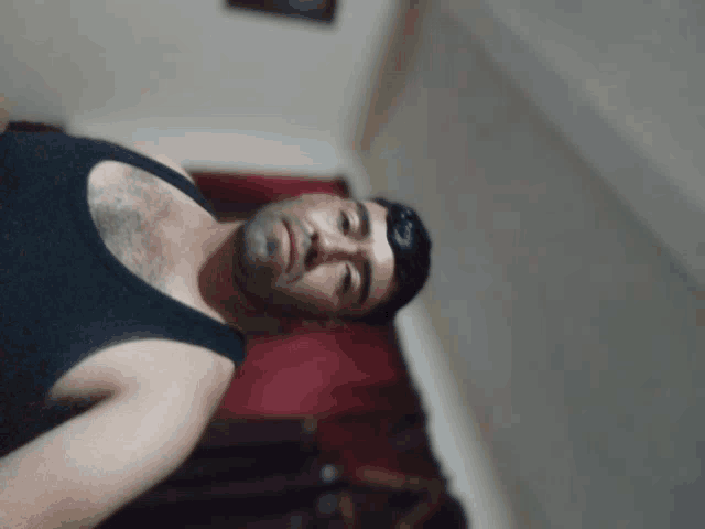 a man in a black tank top is looking down at the camera