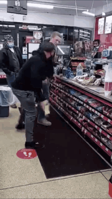 a man is standing in front of a counter in a store talking on a cell phone .