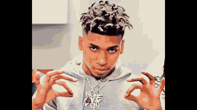 a young man with dreadlocks is wearing a necklace that says no love i kent