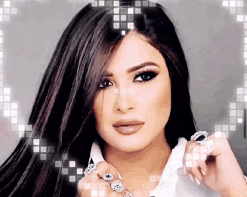 a woman with long dark hair is wearing a white shirt and rings on her fingers