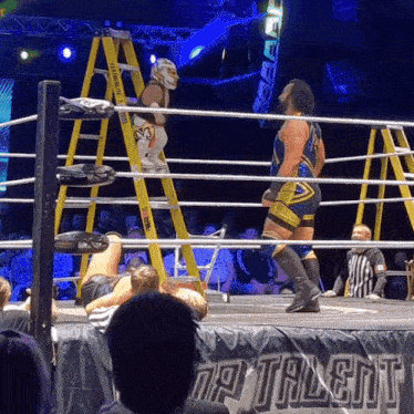two wrestlers in a wrestling ring with a sign that says talent on it