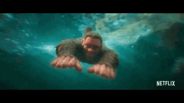 a man is swimming underwater with his hands outstretched .