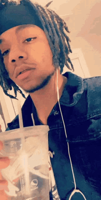 a man with dreadlocks is drinking from a plastic cup that says pepsi