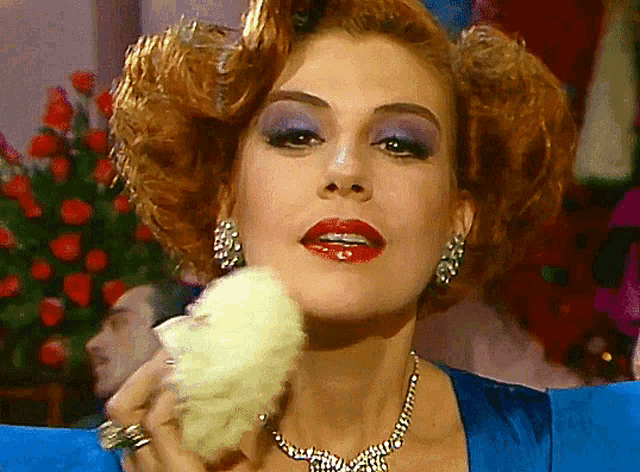 a woman wearing a blue dress and a necklace is holding cotton candy
