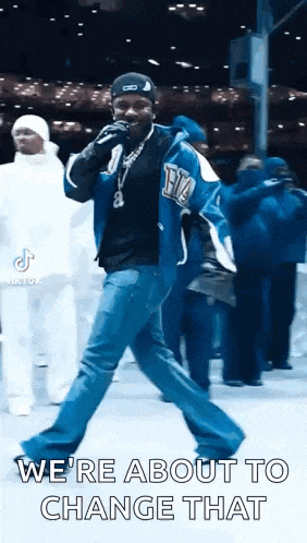 a man in a blue jacket is dancing and singing into a microphone while holding a microphone .