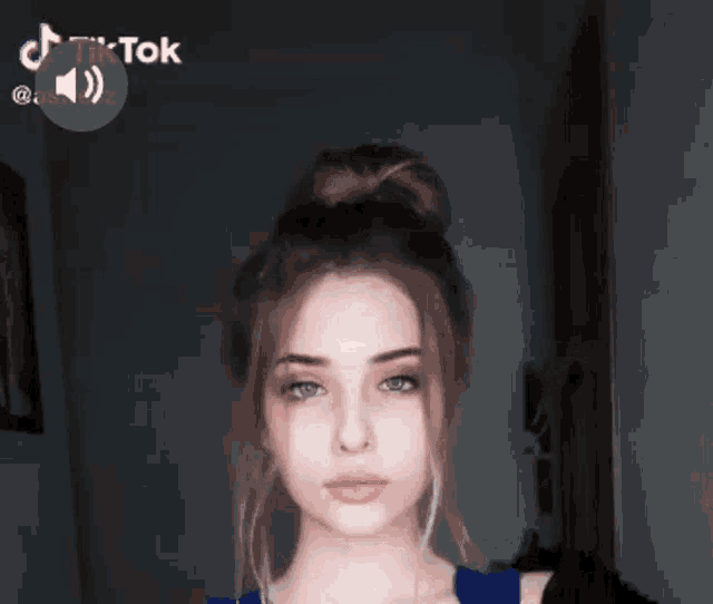 a young woman is making a funny face with her finger on her lips while wearing a blue shirt .