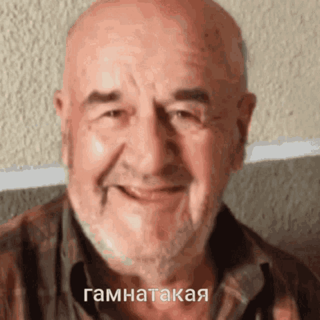 a bald man with a beard is smiling in a close up of his face