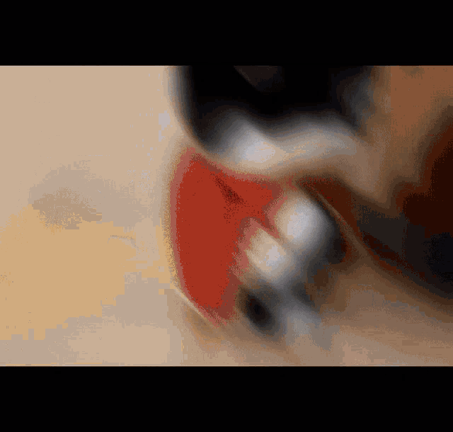 a blurred image of a person 's face with a red object in the background