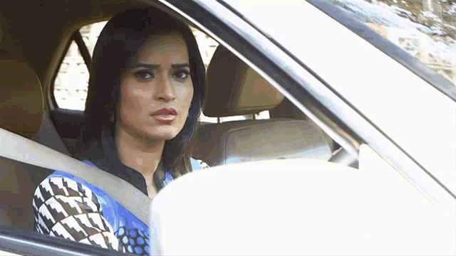 a woman is sitting in the driver 's seat of a car looking out the window