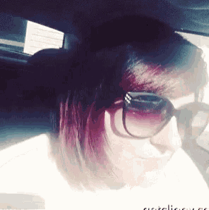 a woman wearing sunglasses and a white shirt is sitting in a car ..